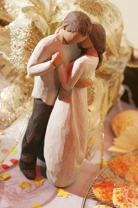 A willow tree figurine of a bride and groom embracing.